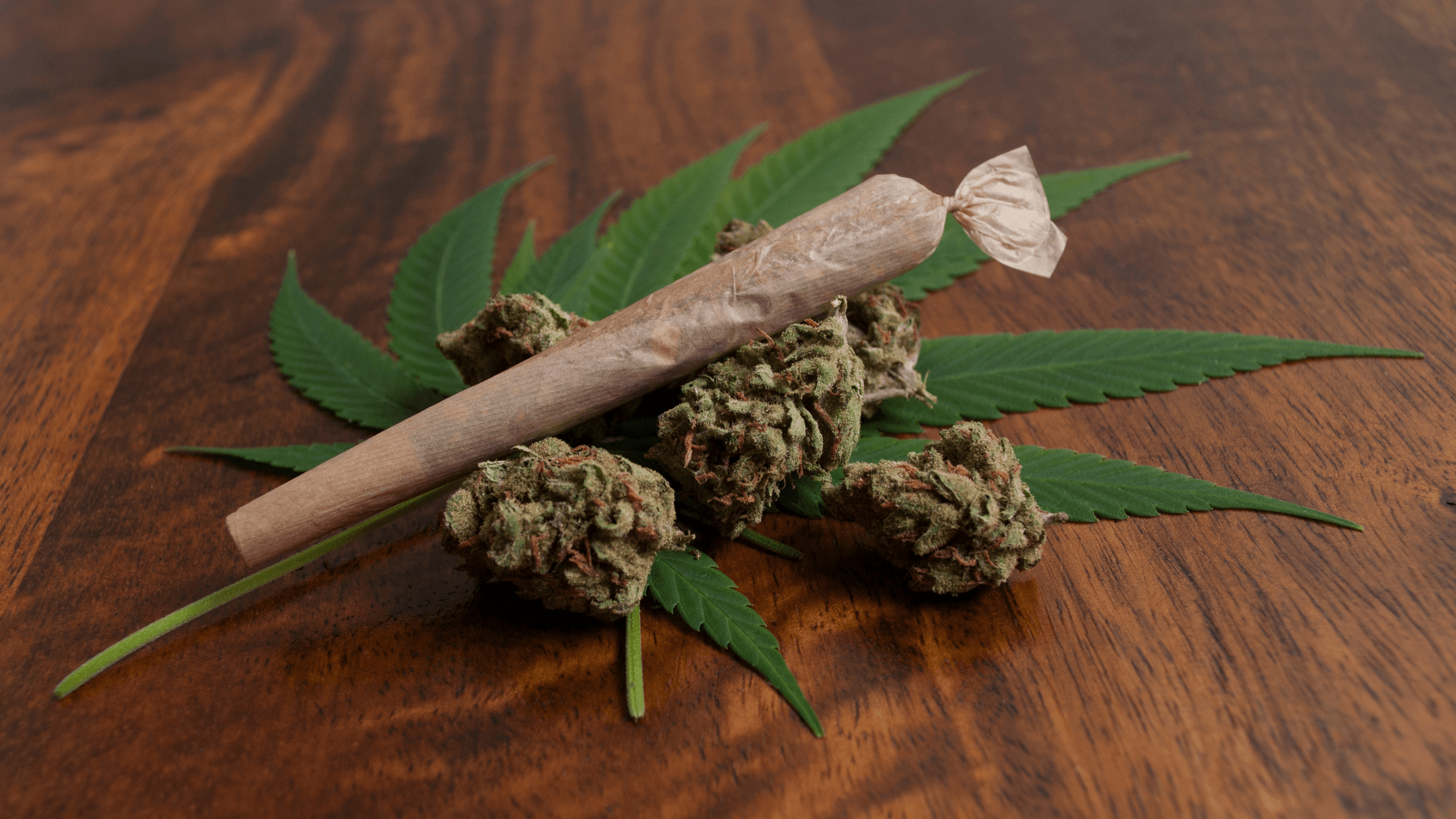 Pre-rolls vs flower comparison image featuring a cannabis joint (pre-roll) and marijuana flower buds on a wooden table