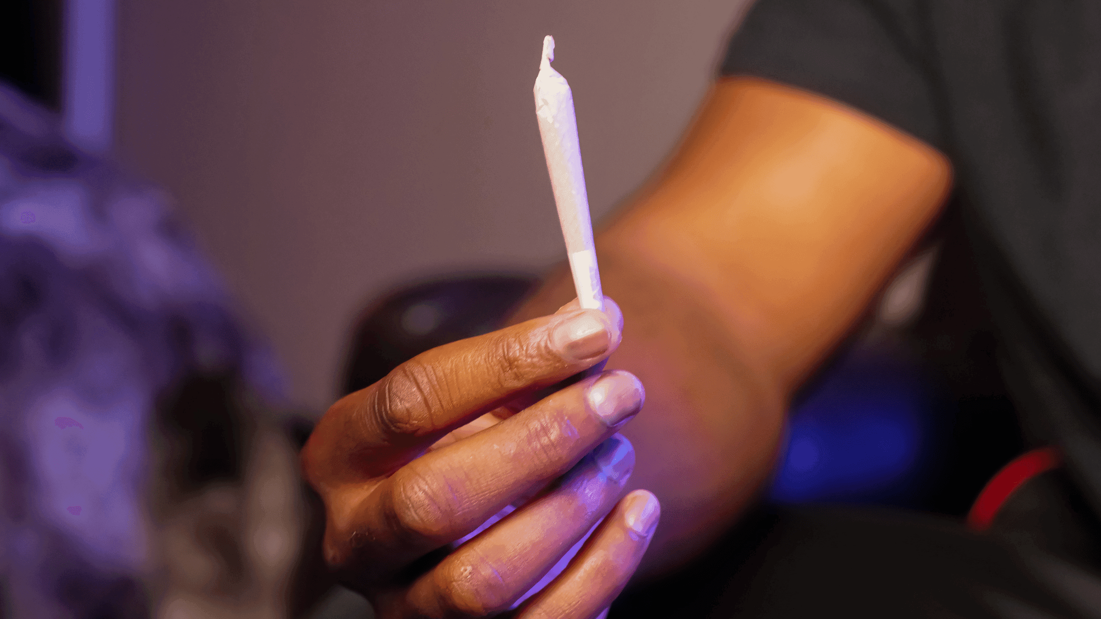 Close-up of a person holding a cannabis pre-roll, highlighting a ready-to-smoke joint as a gift or personal use option