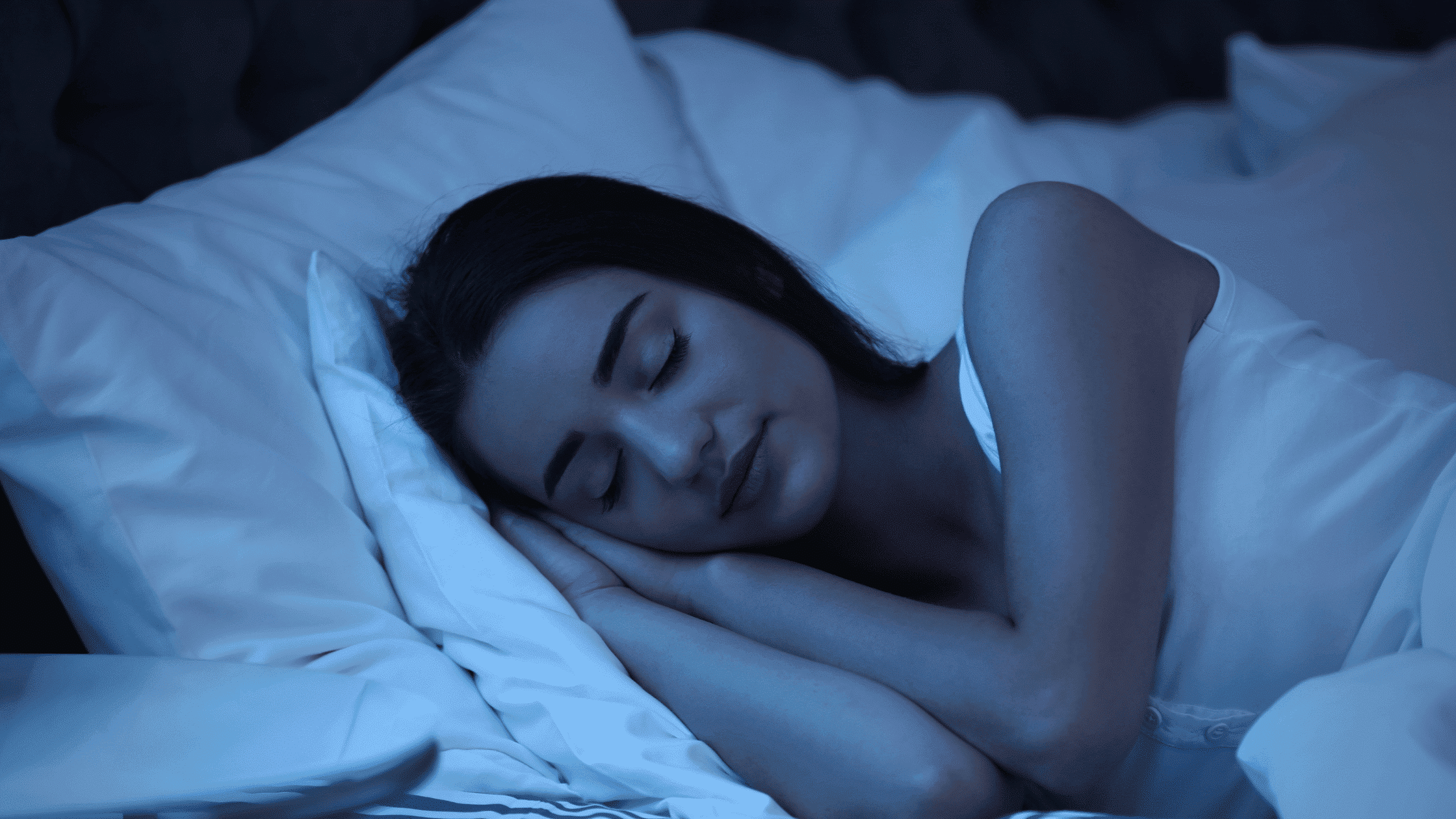 Woman sleeping peacefully in bed, representing the benefits of using the best cannabis strains for sleep